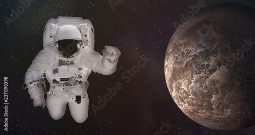 Astronaut in outer space with fiction brown lifeless planet. Science fiction wallpaper. Elements of this image were furnished by NASA.