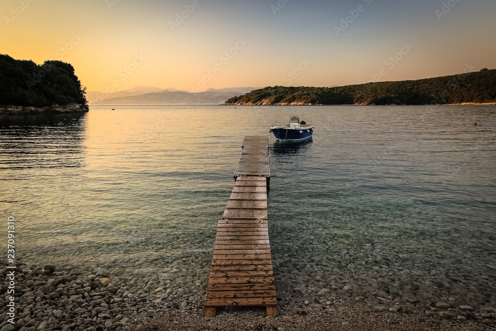 View of the bay at sunset, (golden hour) stony beach with a small jetty to which the boat was moored,