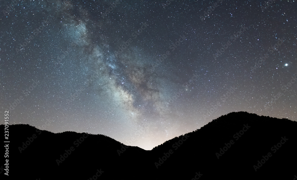 Naklejka Nocny krajobraz z kolorową Drogą Mleczną nad Górami
