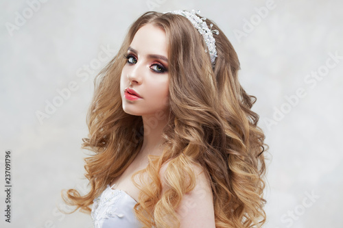 Charming young bride with luxury hairstyle. Beautiful woman in wedding dress. Hairstyle with fluffy curls.