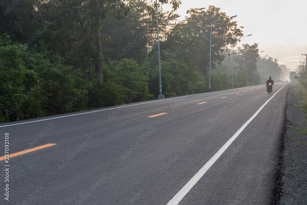 Fototapeta premium Asphalt road with sun rising in the countryside.