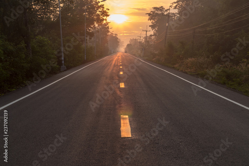 Asphalt road with sun rising in the countryside. © kaentian