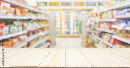 Wood table top with Supermarket convenience store aisle shelves interior blur for background