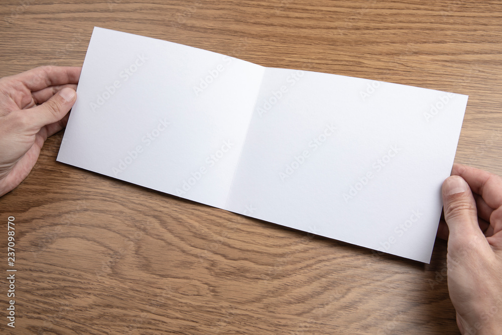 Mens hands holding white booklet Mens hands holding white booklet