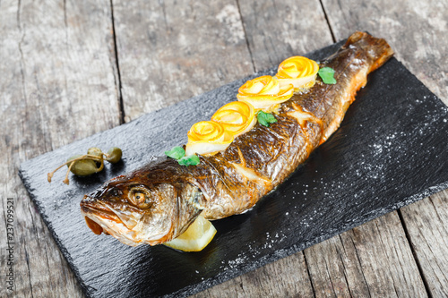 Grilled sea fish with lemon on stone slate background close up. Healthy food. Top view photo