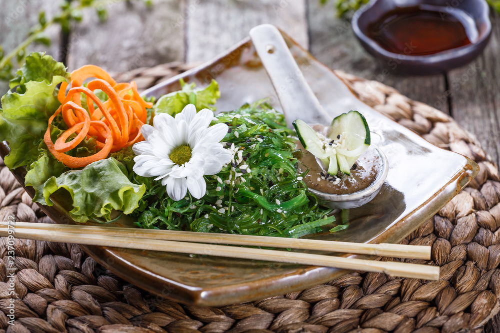 Seaweed Salad wakame in plate with chopsticks on bamboo mat. Japanese Cuisine - healthy sea food Seaweed Salad wakame in plate with chopsticks on bamboo mat. Japanese Cuisine - healthy sea food
