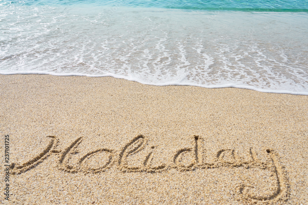 Holiday inscription on a tropical sandy beach with waves and foam on a background. Holiday inscription on a tropical sandy beach with waves and foam on a background.