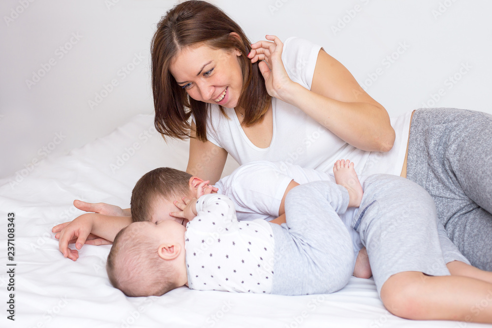 Young mom with her two sons playing on a bed Young mom with her two sons playing on a bed
