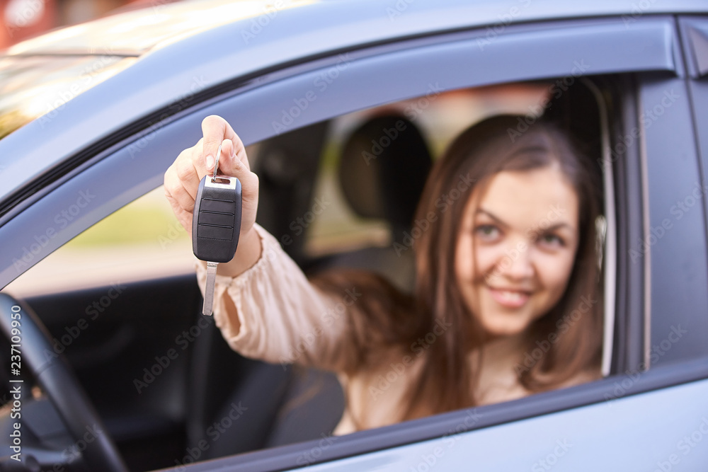 Young woman in car. Ride instruction. Automobile loan. Hand with key