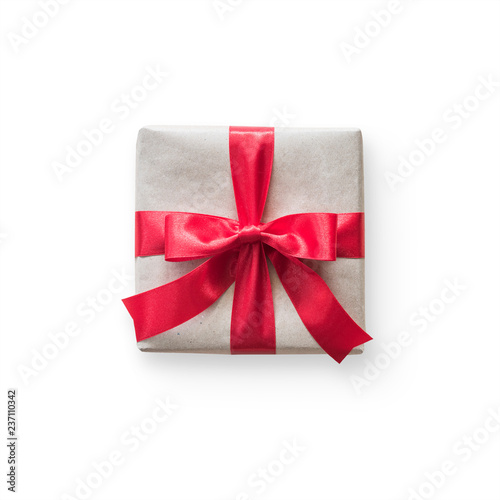 Gift box present (isolated with clipping path) with red bow satin ribbon over brown wrapping paper on white background for Christmas and birthday greeting card design decoration template