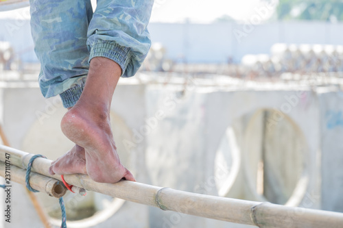 Close up of construction worker's feet treading on a Bamboo Scaffolding, feet with dry heels, cracked skin.