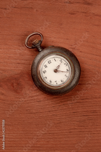 A photo of an old watch, shot from the top on a dark rustic wooden background with a place for text