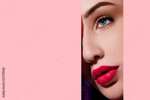 Beautiful woman face in pink paper frame. Plump red lips, blue eyes and clear skin. Fashion and beauty, close up portrait photo