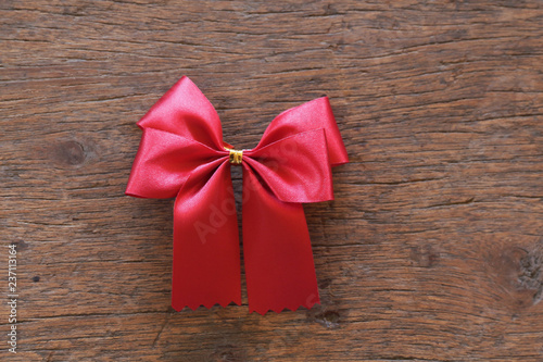 Red ribbon with bow on wooden background