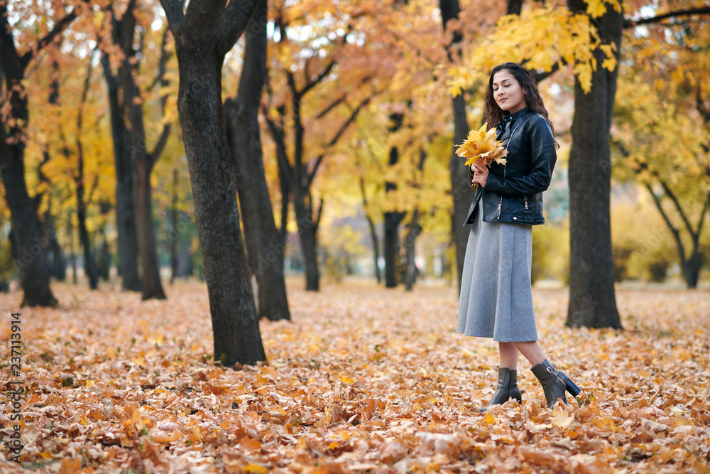 Pretty woman is posing with bunch of maple's leaves in autumn park. She's closing eyes and dreaming. Beautiful landscape at fall season. Pretty woman is posing with bunch of maple's leaves in autumn park. She's closing eyes and dreaming. Beautiful landscape at fall season.