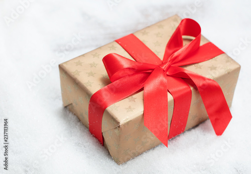 christmas box with red ribbon and bow on snow background