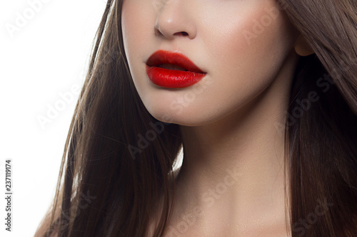 Fototapeta Naklejka Na Ścianę i Meble -  Beauty closeup of women full red lips with shiny skin and long hair. Facial skin care in a spa salon or cosmetology and a fashionable natural lip gloss or lipstick. Day makeup