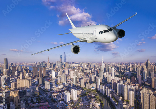 Airplane flying over city business buildings. 