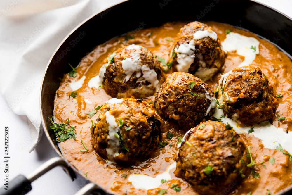 Malai Kofta is a Mughlai Speciality dish served in a bowl or pan over moody background. selective focus