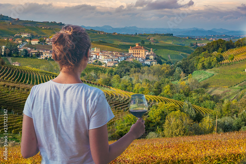 girl holding a glass of red wine looking amazing green vineyards in the italian region of Piedmont, Alba, Barolo town, langhe Monferrato region, Italy photo