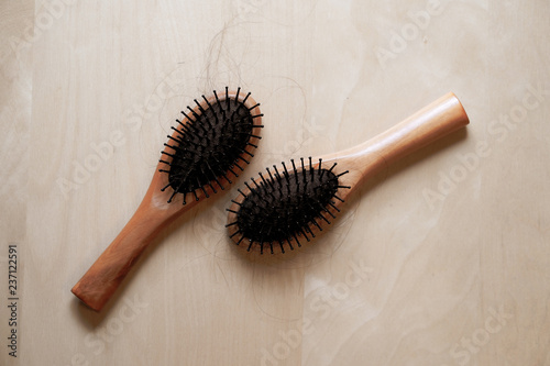 Black hair with wood comb on a wooden table. Concept of hair loss.