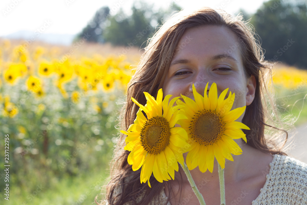 handsome teenage girl brunette with sunflower enjoying nature and laughing on summer sunflower field handsome teenage girl brunette with sunflower enjoying nature and laughing on summer sunflower field