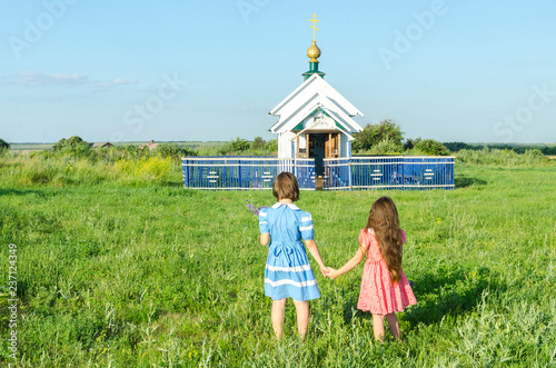 Bilde på lerret Девочки идут в деревенскую часовню взявшись за руки.