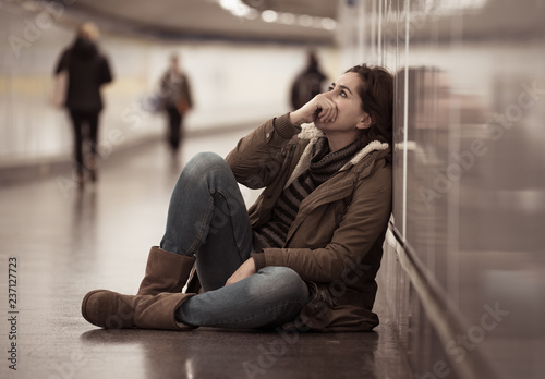 Young depressed woman crying on the ground on subway underground