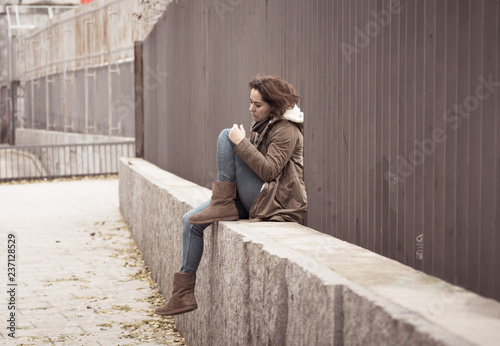 Depressed young woman sitting on urban city street overwhelmed a © SB Arts Media