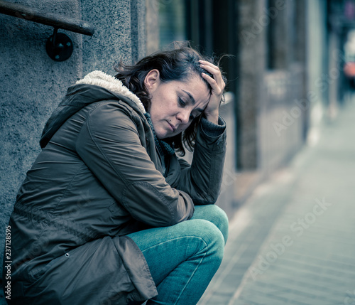 Depressed woman sitting on urban city street overwhelmed and hop © SB Arts Media