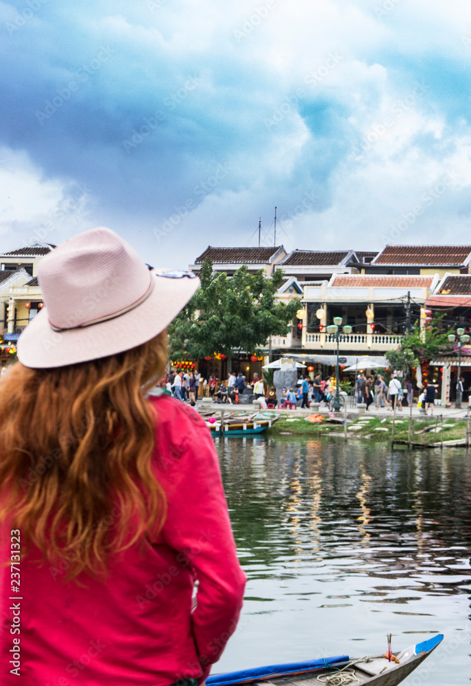 Red hair girl tourist in hat is travelling in Hoi An ,staying on the bridge and looking for architacture and river in Ancient town,Vietnam,Dannang