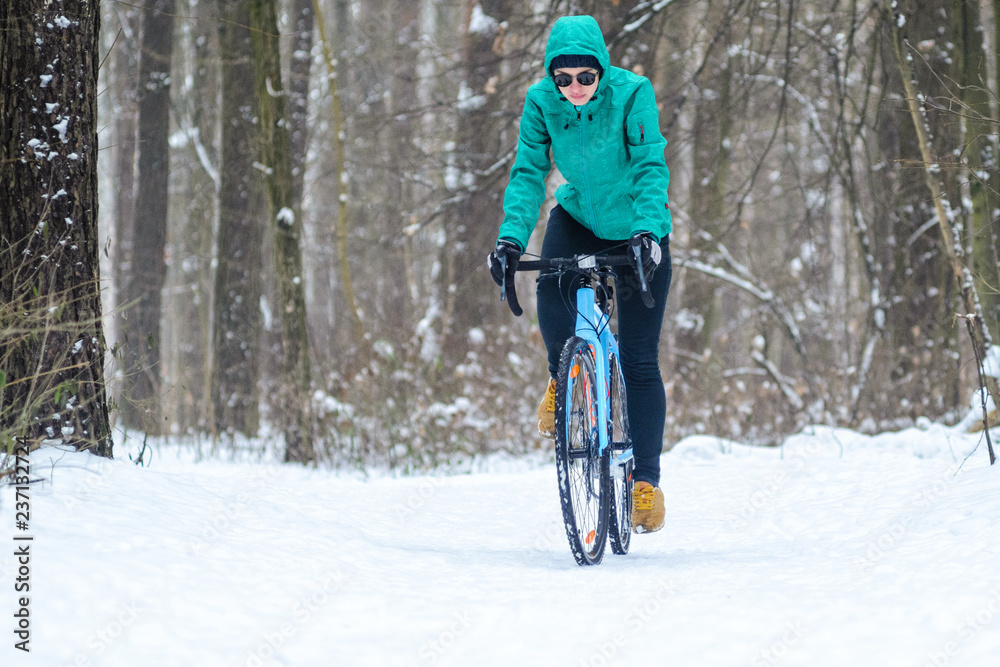 Cyclist on cyclocross bike trails in the snowy forest in winter. Winter workout outdoors concept