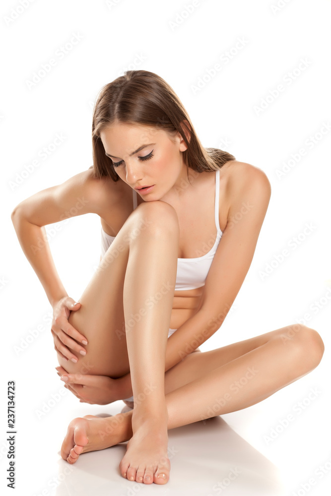 woman tenderly touching her legs on white background woman tenderly touching her legs on white background