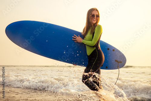 Photography Young freelancing woman in a wetsuit swimming over surfboard in the water at beach