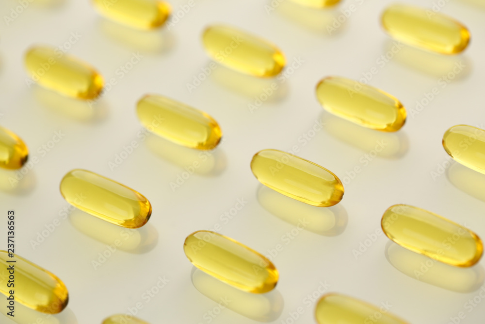 Pile of yellow transparent omega-3 pills arranged in diagonal line Pile of yellow transparent omega-3 pills arranged in diagonal line