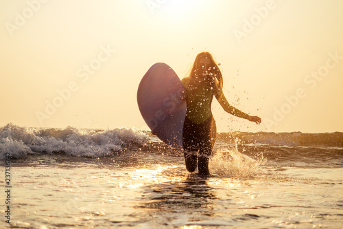 active women with surf board enjoy watersport at vacation holidays.sport girl in surfing school instructor of windsurf. tourist female model in a diving suit wetsuit on the beach in the Indian Ocean