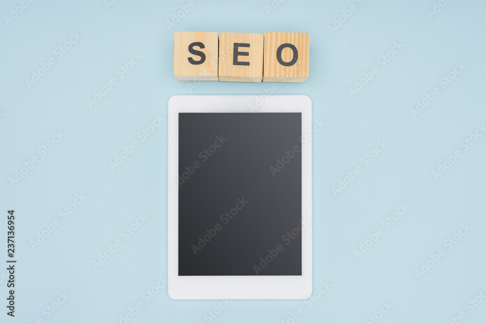 Flat lay of digital tablet with blank screen near wooden cubes on light blue background Flat lay of digital tablet with blank screen near wooden cubes on light blue background