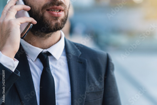 Close-up businessman talking on smartphone against the business building outdoors. photo