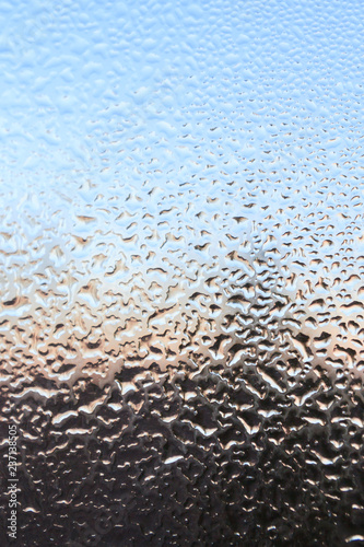 The frozen drops on the patterned frosty winter window