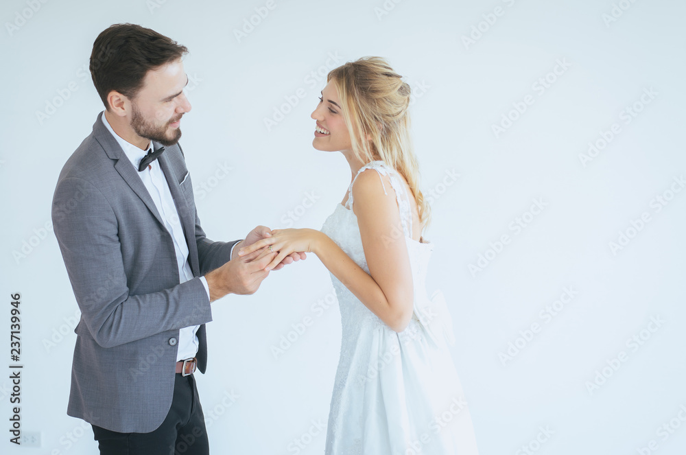 Groom hand putting or wearing a wedding ring to bride finger in wedding day on white background