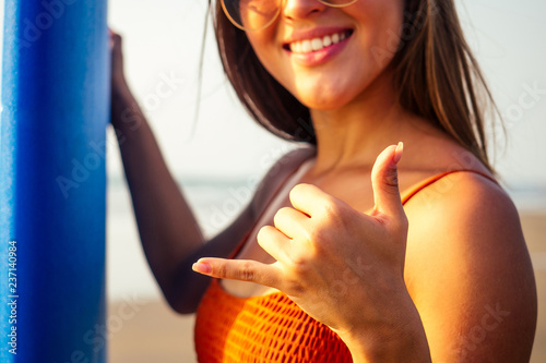 finger hand symbols making a call phone me or aloha greetings surfers.girl surfer on the beach with surfboard
