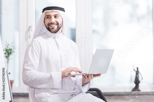 Tablou canvas Arabian businessman holding laptop in modern office