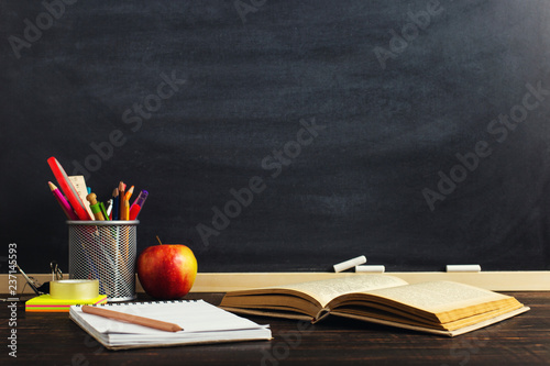Teacher's desk with writing materials, a book and an apple, a blank for text or a background for a school theme. Copy space.