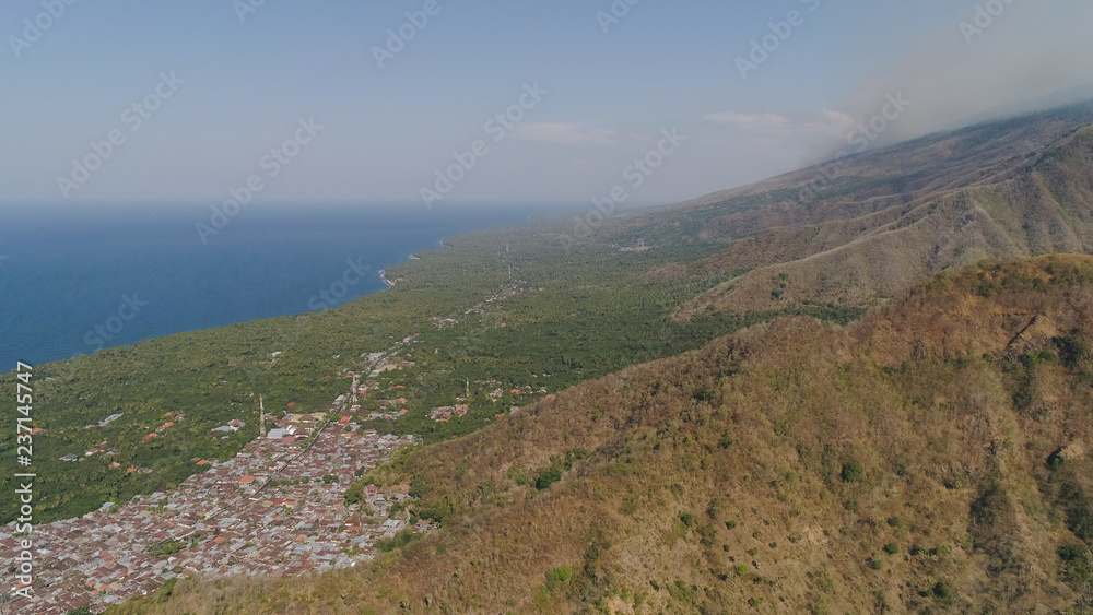 Naklejka premium tropical landscape sea coast with towns, mountain slopes covered with vegetation. Aerial view village by sea Indonesia.