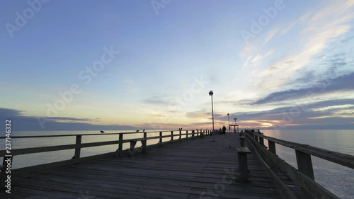 unknown fisherman walking on the pier at sunrise