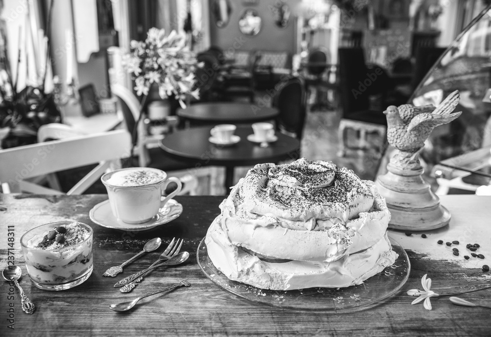 Cake-meringue, dessert and latte coffee on a vintage table in a cafe in a retro style. Black and white photo