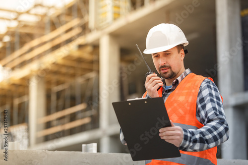 Foto Developing engineer wearing white safety vest and hardhat with walkie talkie and