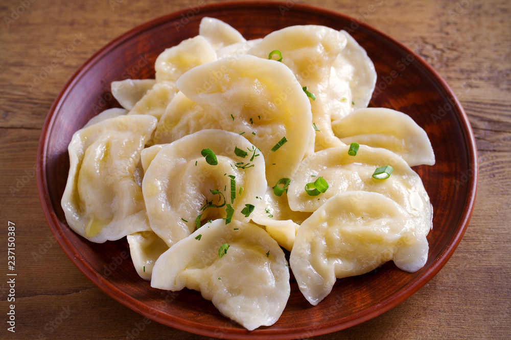 Dumplings, filled with mashed potato in plate on wooden table. Varenyky, vareniki, pierogi, pyrohy - dumplings with filling. Vegetarian dish. horizontal Dumplings, filled with mashed potato in plate on wooden table. Varenyky, vareniki, pierogi, pyrohy - dumplings with filling. Vegetarian dish. horizontal