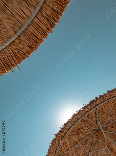 Two Straw Umbrellas and Sun
