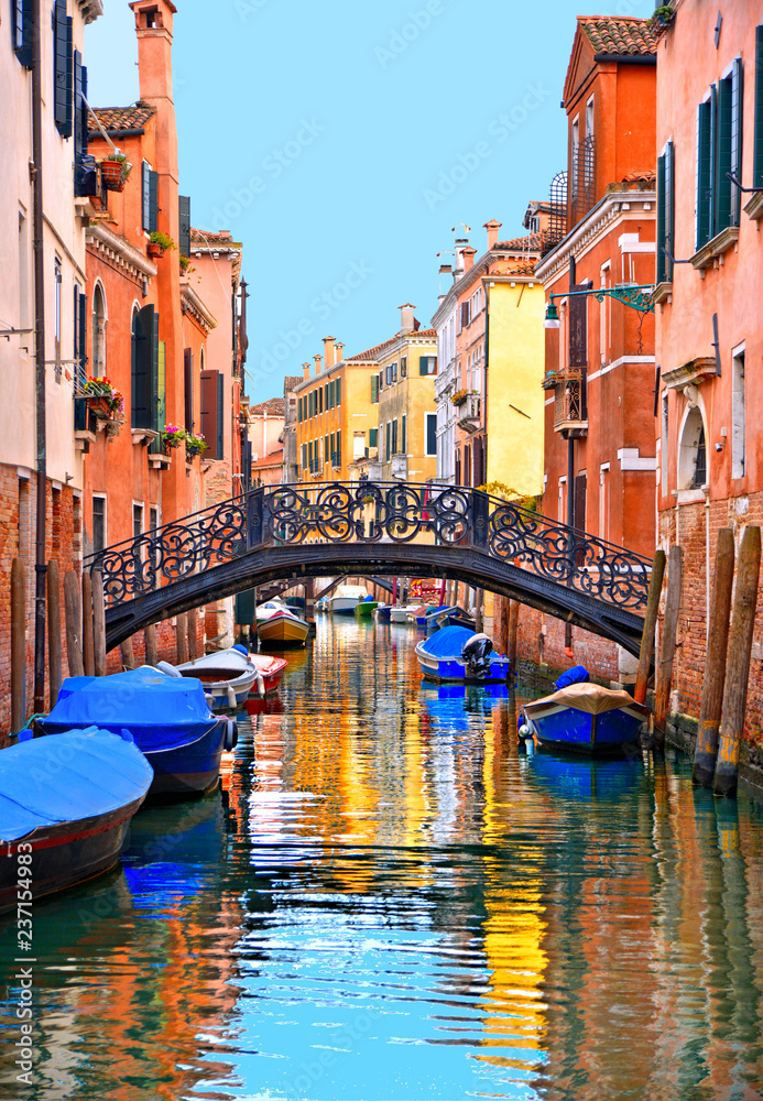 Venice colorful corners with iron bridge, old buildings and architecture, boats and beautiful water reflections on narrow canal, Italy